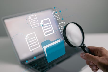 magnifying glass in front of a laptop screen full of documents and folders since Historical Data Preservation is available