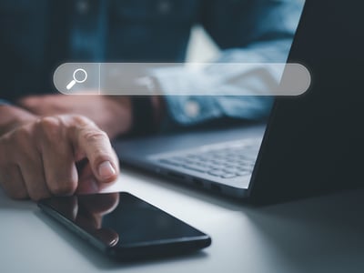 person reachign for a mobile device next to a laptop since Instant Search can scan files