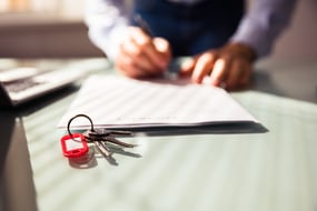 keys on a key ring next to a person signing a key holder contract 