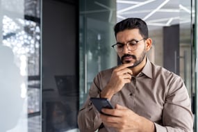 hispanic male looking at credentials audit on his phone