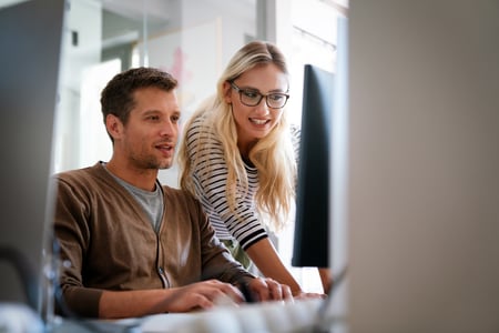 2 cowokers collaborate while looking at a computer