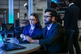 male and female IT professional integrating data and ID governance via computer
